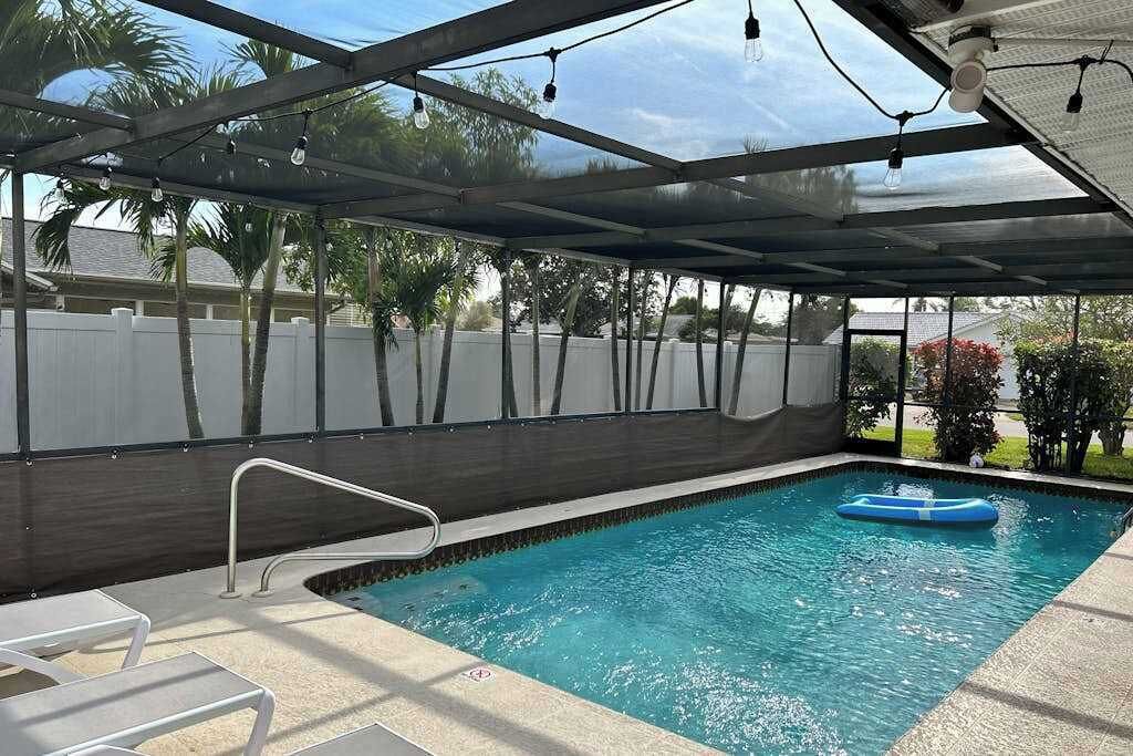 Una piscina interior con techo de cristal, una escalera de piscina y un flotador.