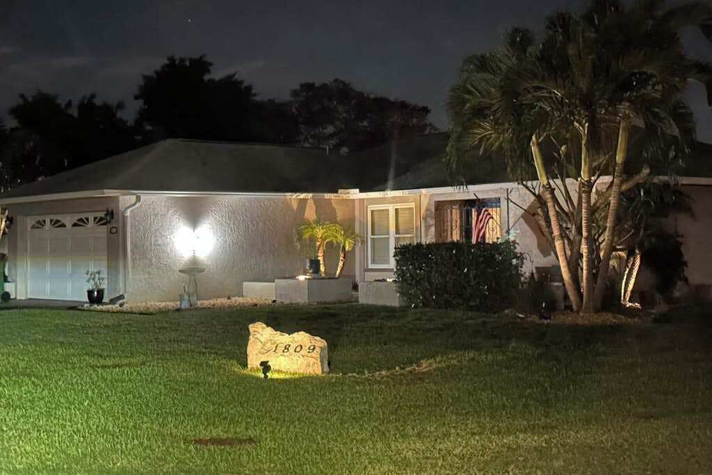 A house with a well-maintained lawn, a stone marker, and a flag.