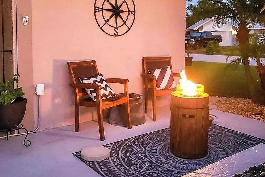 Un patio con dos sillas de madera, un adorno de brújula en la pared y una vela encendida en un barril de madera.