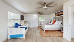 A bedroom with a white bed, a blue chair, a white wardrobe, and a ceiling fan. - Spacious private home with  heating optional pool, patio, and large yard (Bradenton)
