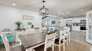 A spacious kitchen with white cabinetry, a wooden dining table, and a hanging light fixture. - Spacious private home with  heating optional pool, patio, and large yard (Bradenton)