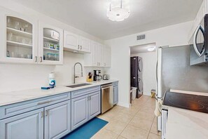 A modern kitchen with white cabinets, a stainless steel refrigerator, and a built-in oven. - Boho Townhome Near Beach | Bikes & Beach Gear Included | Free Parking | W/D (Bradenton)