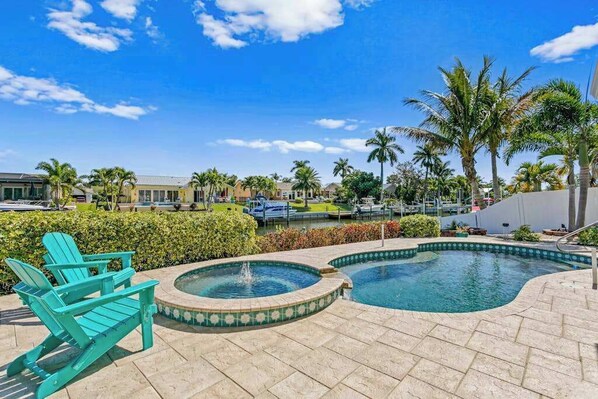 A pool area with a fountain, lounge chairs, and palm trees. - Canal front home with boat access and and private pool and spa with fountain (Bradenton)