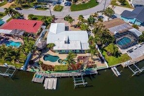 An aerial view of a residential property with a swimming pool, dock, and a large house with a red roof. - Canal front home with boat access and and private pool and spa with fountain (Bradenton)
