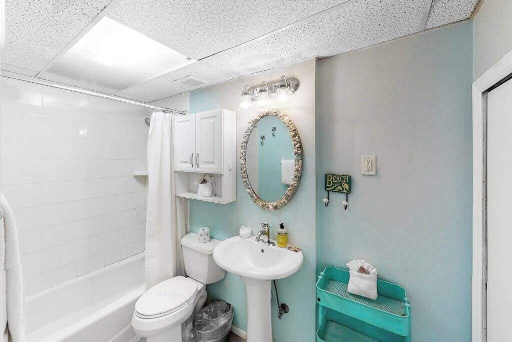 Un bagno con un WC bianco, un lavandino, una vasca da bagno, uno specchio e un portascope.