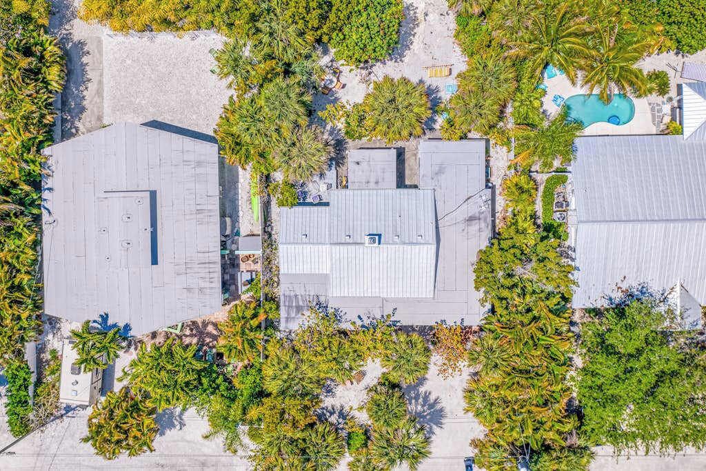 An aerial view of a property with multiple buildings, surrounded by dense greenery and a swimming pool.