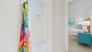Una habitación con ducha, cama y mesita de noche.