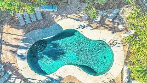 Una piscina circular de borde ondulado, rodeada de sillas de descanso y un patio empedrado.