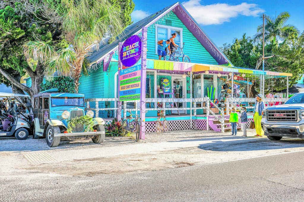 Un edificio colorido con un letrero que dice 'Beach Bums' y un pequeño porche.