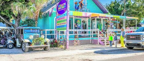 Un edificio colorido con un letrero que dice 'Beach Bums' y un pequeño porche.