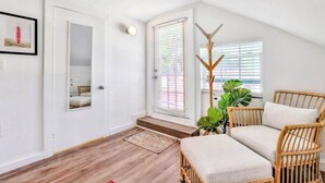 Ein Zimmer mit Holzboden, einer weißen Tür, einem Spiegel, einer Bank und einer Pflanze.
