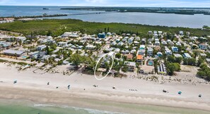 An aerial view of a coastal residential area with houses, a beach, and a pier in the background. - Luxury oceanfront home w/ pool, spa, free parking (Holmes Beach)