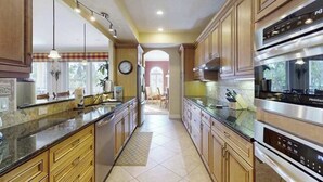 Eine Küche mit Holzausstattung, einem Edelstahlkühlschrank und einem eingebauten Backofen.