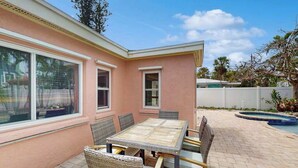 Et pink hus med en patio, en pool og et bord med stole.