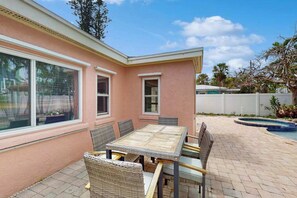 A pink house with a patio, a pool, and a table with chairs. - Dog-friendly seaside home - heated private pool & spa, great location near beach (Holmes Beach)