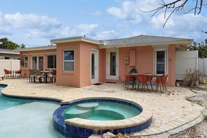 Il s’agit d’une propriété résidentielle dotée d’une piscine, de meubles de jardin et d’un petit bâtiment avec une porte et des fenêtres.