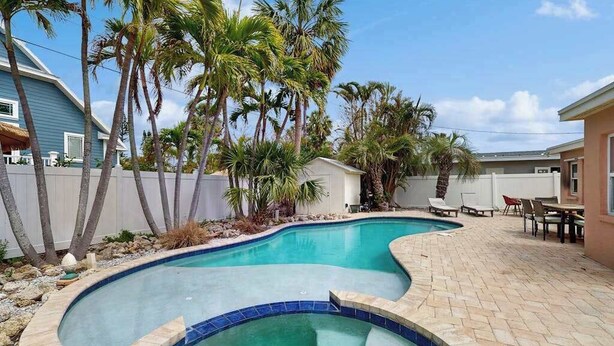 En swimmingpool med et bølgende design, omgivet af palmer og en belægning af mursten.