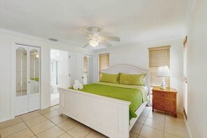 Une chambre à coucher comprenant un lit, un ventilateur de plafond, une table de chevet et une armoire.