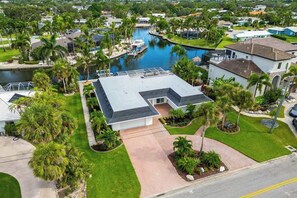 A residential area with a house featuring a flat roof, a driveway, and a well-maintained lawn. - Waterfront retreat with pool ,dock, family friendly, steps to the Gulf, WD (Siesta Key)