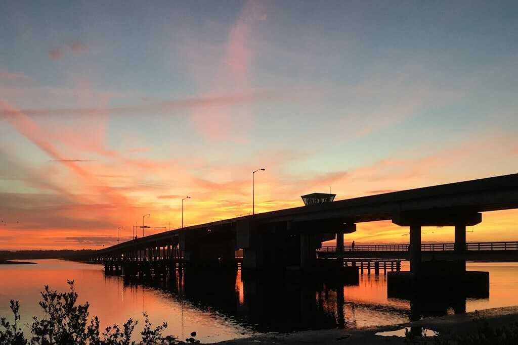A bridge over water during sunset with clear skies.
