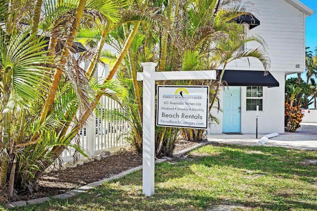 A sign for Parrot Beach Cottages at 60 Avenida Venecia, offering beach rentals.