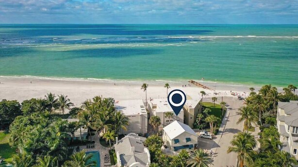 Een hotel aan de kust met uitzicht op het strand, palmbomen en een heldere lucht.