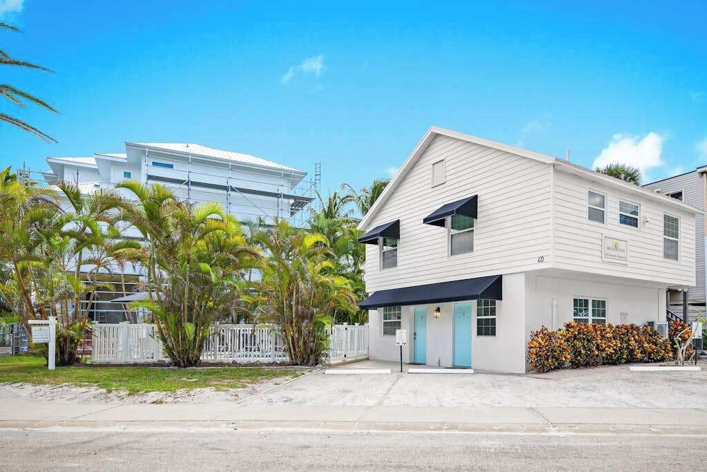 A two-story building with a flat roof, a light blue door, and a small porch area.