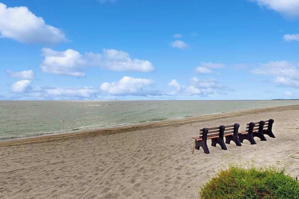 Une plage bordée d’une rangée de bancs donnant sur la mer.