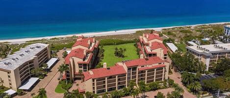 A hotel with a central courtyard, multiple buildings with red roofs, and a beach view.