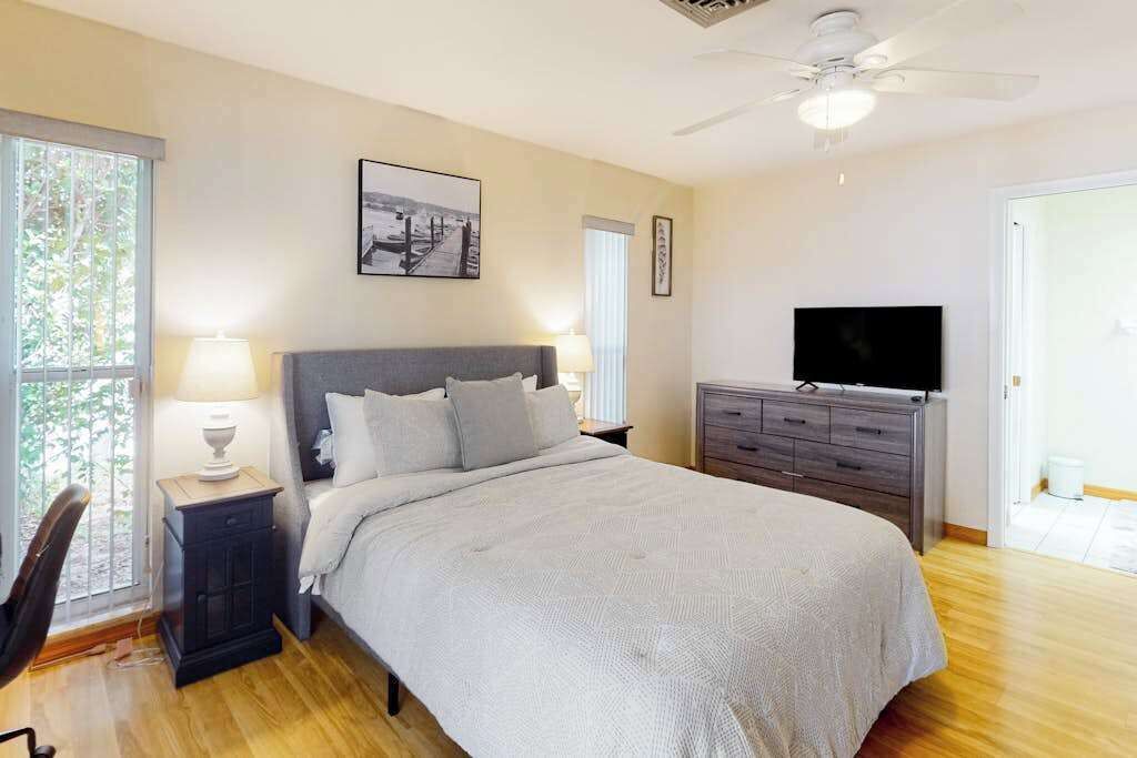 Una camera da letto con un letto, lampade sui comodini, una cassettiera, una televisione e una ventola a soffitto.