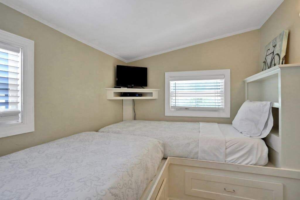 Un dormitorio con dos camas, televisión y ventana.