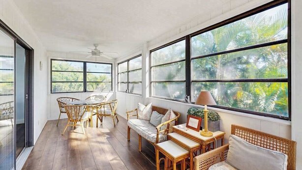 A sunlit room with large windows, wicker furniture, and a ceiling fan. - Newly-Renovated, Dog-Friendly Home w Private Heated Pool & Streaming Services (Anna Maria)