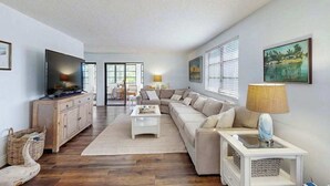 A living room with a sofa, a TV, a lamp, and a painting on the wall. - Newly-Renovated, Dog-Friendly Home w Private Heated Pool & Streaming Services (Anna Maria)