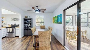 A modern kitchen with a dining area, a ceiling fan, and a view through a glass door. - Newly-Renovated, Dog-Friendly Home w Private Heated Pool & Streaming Services (Anna Maria)