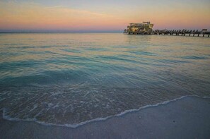 A coastal scene with a pier extending into calm waters, a building on the pier, and a clear sky. - Oceanview getaway with pool & private patio - steps from the beach (Holmes Beach)