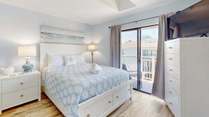 Ein Schlafzimmer mit Bett, Nachttischen, einem Schminktisch und einem Balkon mit Aussicht.