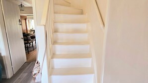 A white staircase leading to an upper floor with a light fixture above. - Cosy Cottage with river stream in Matlock (Matlock)