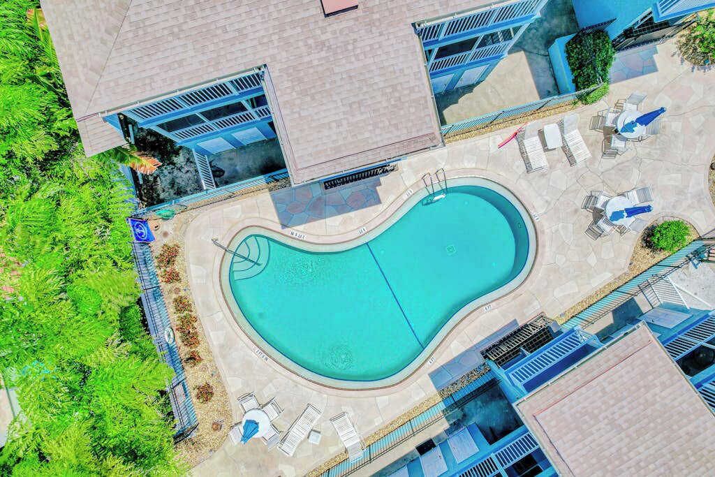 Ein Luftbild eines Hotels mit Schwimmbad, Liegestühlen und einem überdachten Außenbereich.