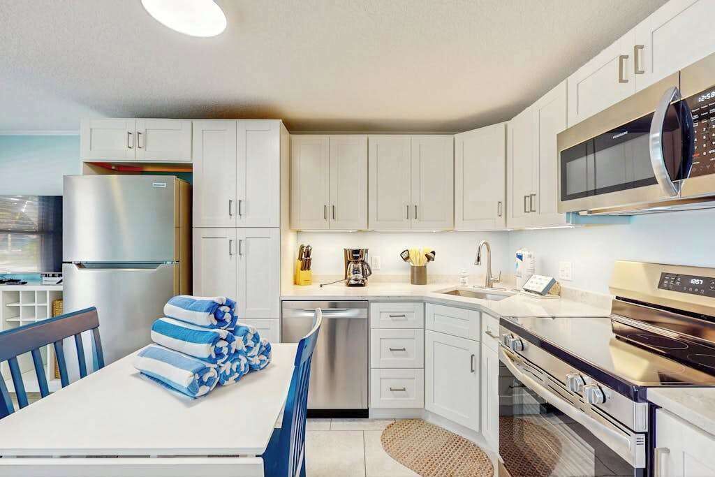 A modern kitchen with white cabinets, stainless steel appliances, and a dining area with a table and chairs.