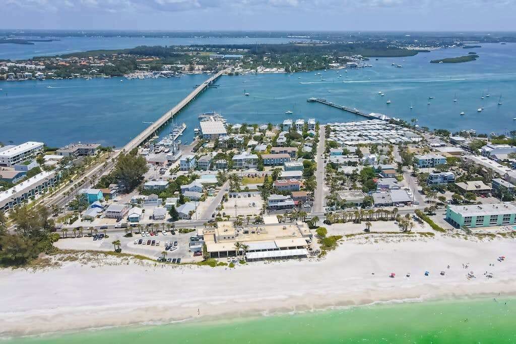 Luftaufnahme einer Küstenstadt mit Hafen, Strand und Wohnhäusern.