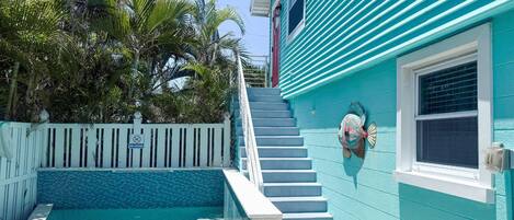 A turquoise building with a pool, a white fence, and a no diving sign.
