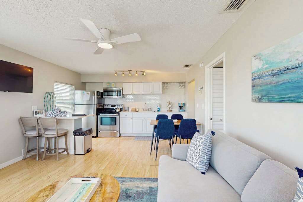 A modern kitchen with white cabinets, a microwave, and a dining area with chairs and a table.