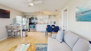 Een moderne keuken met witte kasten, een magnetron en een eethoek met stoelen en een tafel.