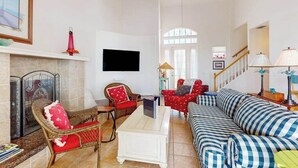 Un salon avec une cheminée, un téléviseur, un canapé et un fauteuil.