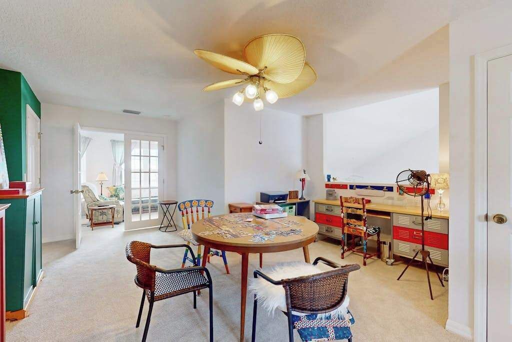 A dining area with a round table, chairs, and a ceiling fan.