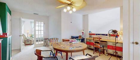 A dining area with a round table, chairs, and a ceiling fan.