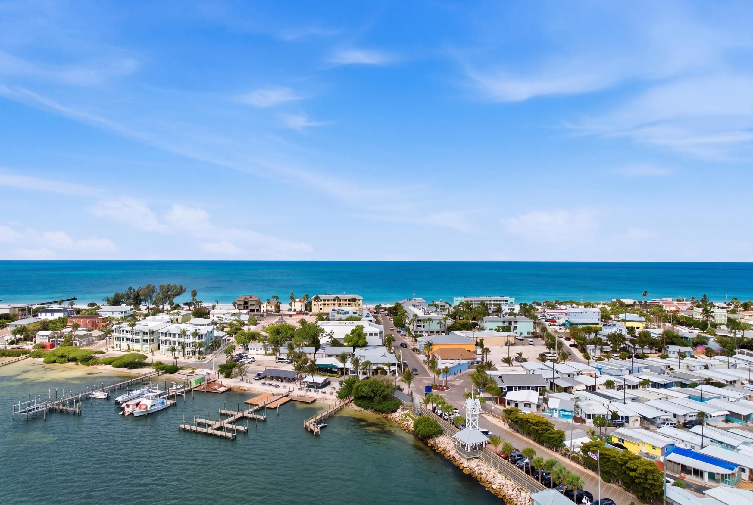 Un pueblo costero con un puerto deportivo, edificios residenciales y una vista despejada del océano.