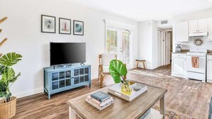A living room with a TV, blue cabinet, and a coffee table with books and a plant.