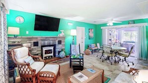 Un salón con chimenea, televisor y comedor con sillas y mesa.