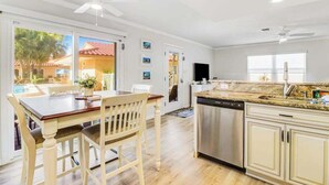 A kitchen with a dishwasher, a dining table with chairs, and a ceiling fan. - Charming Ground Floor Condo with Shared Pool, High-Speed WiFi, and Central AC (Holmes Beach)